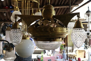 Antique chandelier at Tbilisi flea market. Old brass chandelier with ornate metal details and glass shades hanging at a flea market in Tbilisi, Georgia. Vintage decor concept.