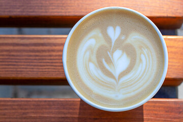 Warm latte with heart latte art in a ceramic cup on a wooden table