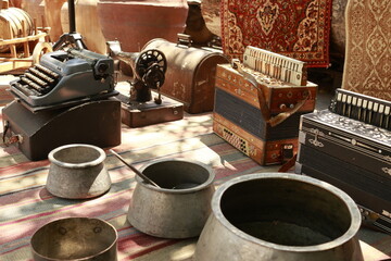 Old typewriter, sewing machine, accordions, and metal pots displayed at the Dry Bridge flea market in Tbilisi, Georgia. Vintage collectibles symbolizing heritage and craftsmanship.