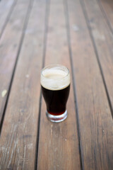 A glass of dark beer on wooden table