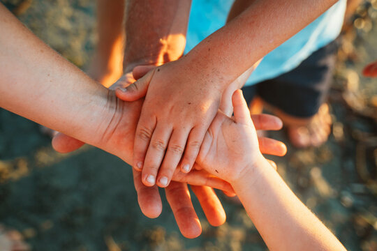 Hands from different individuals come together in a supportive gesture, symbolizing unity and teamwork. The image captures a moment of connection, cooperation, and mutual support.