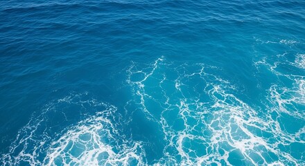 Aerial view of deep blue ocean water with white sea foam patterns creating a dynamic texture effect