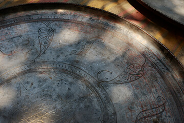 Antique copper trays and dishes with detailed engraving displayed at a flea market in Tbilisi. Warm...
