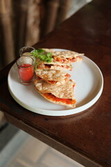 Enjoy delicious quesadillas served with dipping sauces on a rustic wooden table, perfect for a casual lunch or a tasty appetizer to share now