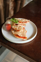 Enjoy delicious quesadillas on a rustic table, accompanied by flavorful sauces and garnished with fresh herbs, perfect for a tasty lunch or dinner