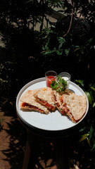 Delightful quesadilla slices with vibrant sauces served outdoors in natural sunlight, perfect for culinary blogs and restaurant promotions