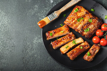 Hot grilled spare ribs from a summer BBQ served on a plate with sauce. Top view. Copy space