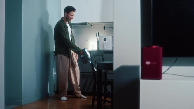 Man vacuuming floor and enjoying music from smart speaker at home