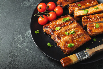 Hot grilled spare ribs from a summer BBQ served on a plate with sauce. Top view. Copy space
