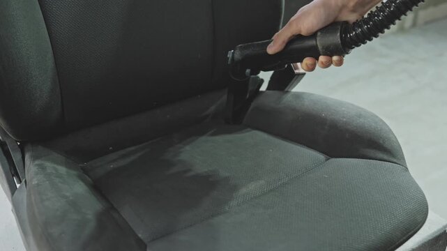 Detailer carefully vacuums car seat In workshop, ensuring every corner is clean and fresh. Transforming dirty car seat into fresh and clean space with washing techniques. Close-up in 4K, UHD