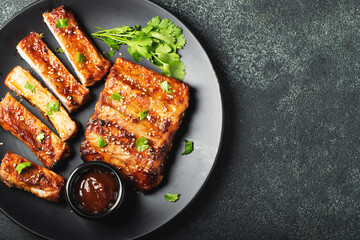 Hot grilled spare ribs from a summer BBQ served on a plate with sauce. Top view. Copy space