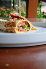 Delicious wrap filled with savory meat and fresh greens, perfect for a satisfying lunch or quick dinner, presented beautifully on a plate