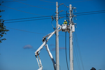man on bucket crane working on high voltage power lines