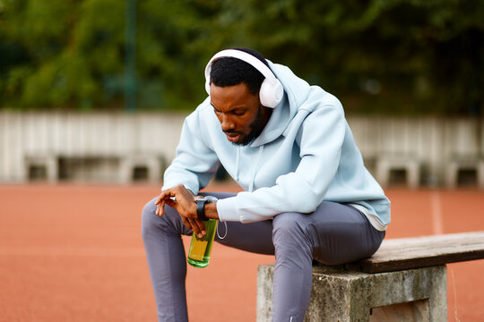 Male athlete resting after training looking smart watch