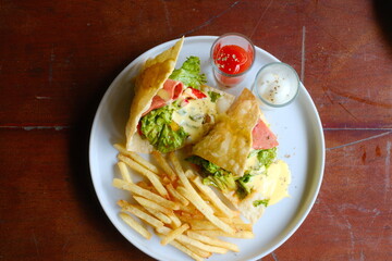 Delicious pita wraps with ham and lettuce served with fries and dipping sauces for a satisfying lunch or dinner, a tasty indulgence