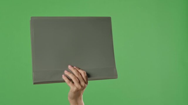 A woman hand holding a gray office folder with documents on a green chroma key background. Shot for designs related to office, business, education, and training.