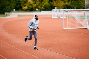 Fototapeta premium Young black man running on athletic track