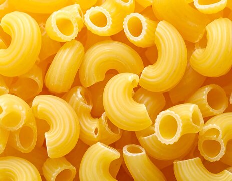 Close-up view showcasing a pile of curved, hollow pasta shapes. Bright yellow, uncooked, and filling the entire frame