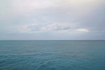 Expansive view of the Caribbean Sea under a soft, overcast sky, highlighting layers of blue and gentle waves, captured from a Royal Caribbean Cruise during calm tropical weather