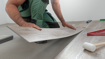 Floating floor work. The worker inserts the board of vinyl plank to the click system of Floating floor.