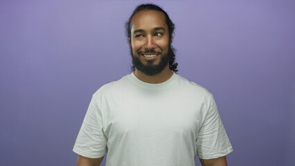 Man smiling with beard and white t shirt in purple studio set, looking at camera; friendly optimism...