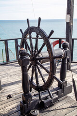 The steering wheel of an ancient wooden ship on a clear sunny day is the marine equipment of the...