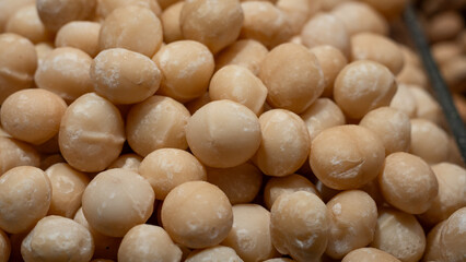 A close-up view of macadamia nuts, emphasizing their round shape and creamy texture. Perfect for food industry use, nutrition blogs, or concepts about superfoods and natural fats.