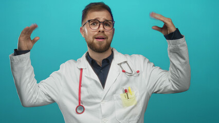 Naklejka premium Young man doctor with red stethoscope raises hands showing palms and smiles in turquoise studio; confidence friendly care.