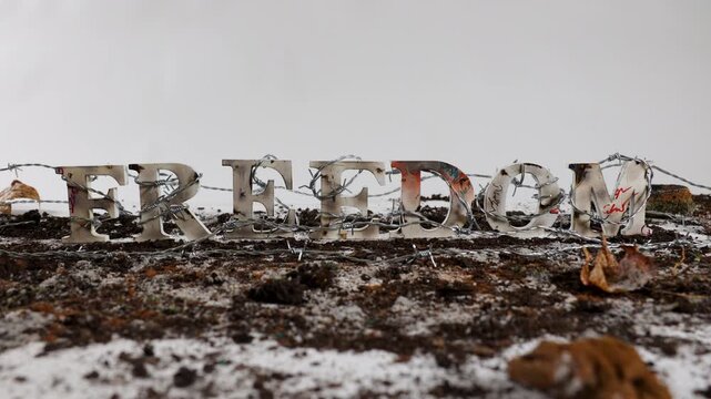 Barbed wire wraps around the word freedom against white background