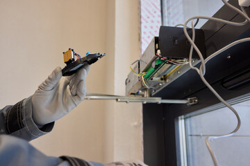 A technician is repairing an advanced automated door system with electrical tools