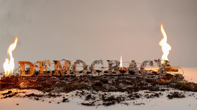 Barbed wire wraps around the word democracy against white seamless