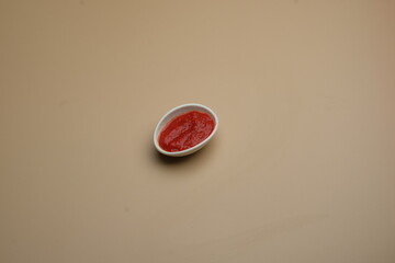 A small bowl filled with sauce placed on a neutral