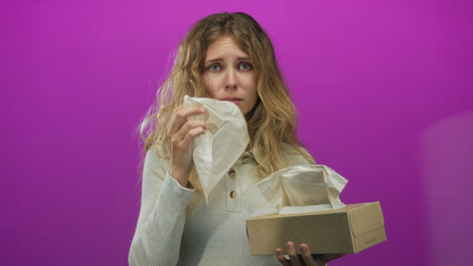 Woman tissue pulling in a studio conveys a blonde young sad mood with a box on a purple background.