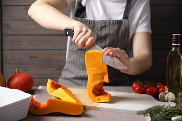 Woman cutting fresh pumpkin at table, closeup