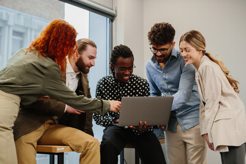 Diverse business team collaborating on laptop in modern office