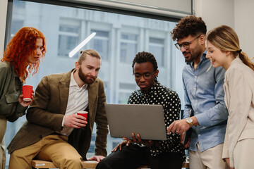 Diverse business team collaborating using laptop in office