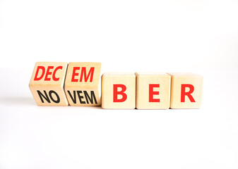 Fototapeta premium Symbol for the change from November to December. Businessman turns wooden cubes and changes the word November to December. Beautiful white background. Happy December concept. Copy space.