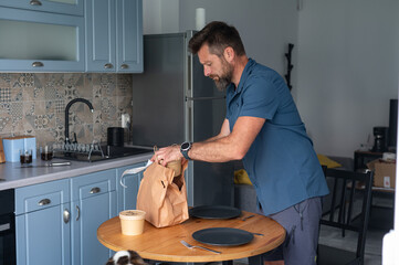 Man Setting Takeaway Food Containers on Kitchen Table