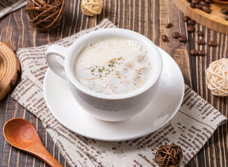 Enjoy warm, comforting creamy mushroom soup. A delicious, elegant meal perfect for cooler weather. Features rustic wooden spoon and coffee beans for a cozy, inviting scene.