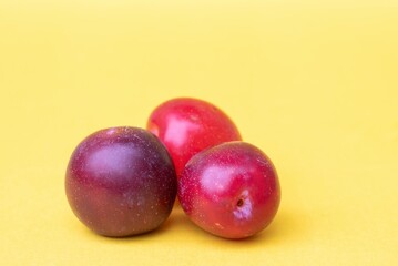 Aloo Bukhara Fruit or Plum Fruit Isolated on Reddish Background with Copy Space