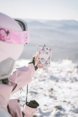 A pink thermos in a woman's hands against a background of mountains