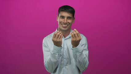 Young hispanic man holds both hands in money gesture against a pink studio wall; playfulness...
