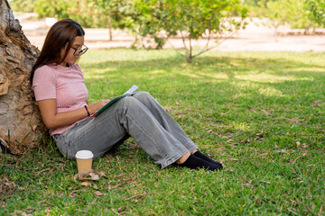 Obraz premium Teenage girl studying notes under a park tree