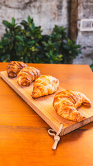 Beautifully presented golden brown, crispy croissants on a wooden board, fresh from the oven and ready to eat. Perfect for bakery promotions and breakfast menus.