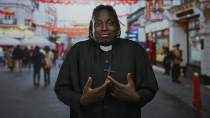 Man priest in black cassock and clerical collar with cross necklace shrugging with palms up on a busy street; bemusement humility.