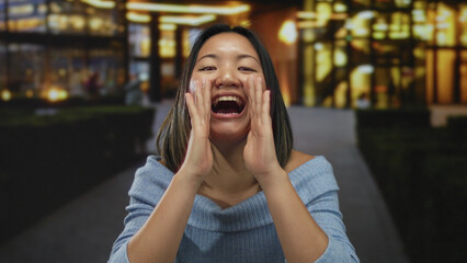 Young woman shouting on busy city street at night, illuminated by glowing urban lights, expressing emotions energetically in an outdoor public setting.