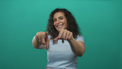 Young hispanic woman points finger to camera in studio setting; confidence motivation empowerment...