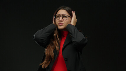 Obraz premium Young woman in glasses feeling stressed over isolated black background, dressed in formal attire displaying frustration and anxiety in an expressive manner.