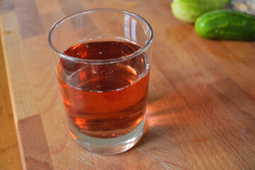 Glass of Clear Amber Liquid on a Wooden Cutting Board