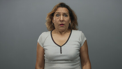 Woman holds up palms toward camera in a studio environment with a grey backdrop, showing a defensive stance; fear.